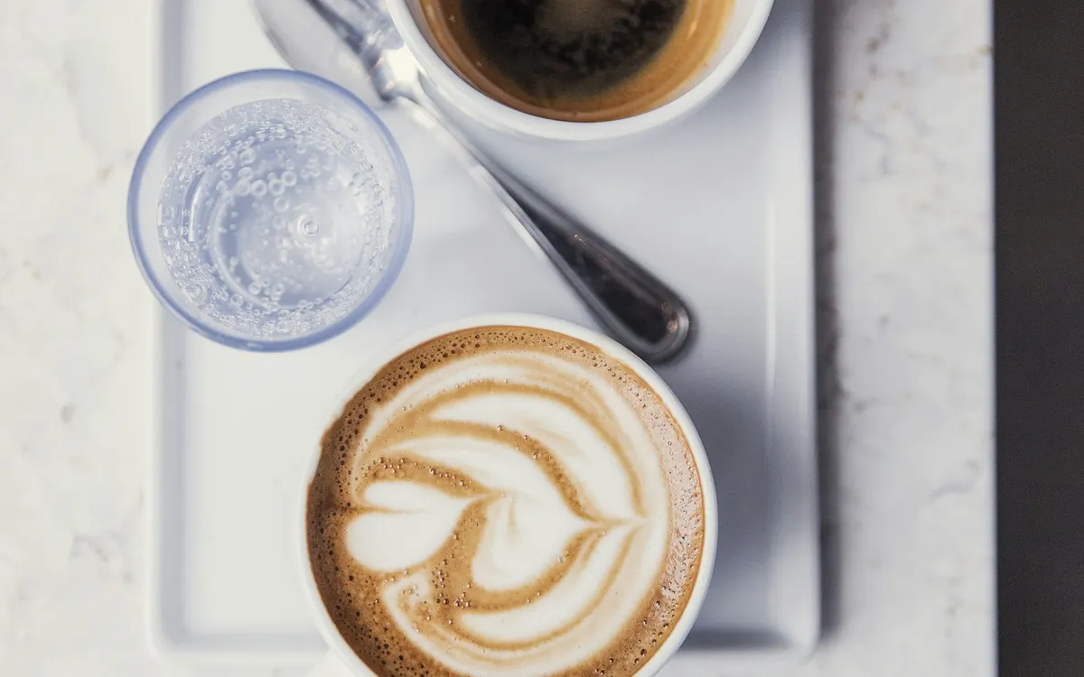 Two cups of coffee and a glass of water on a tray; illustrative stock photo