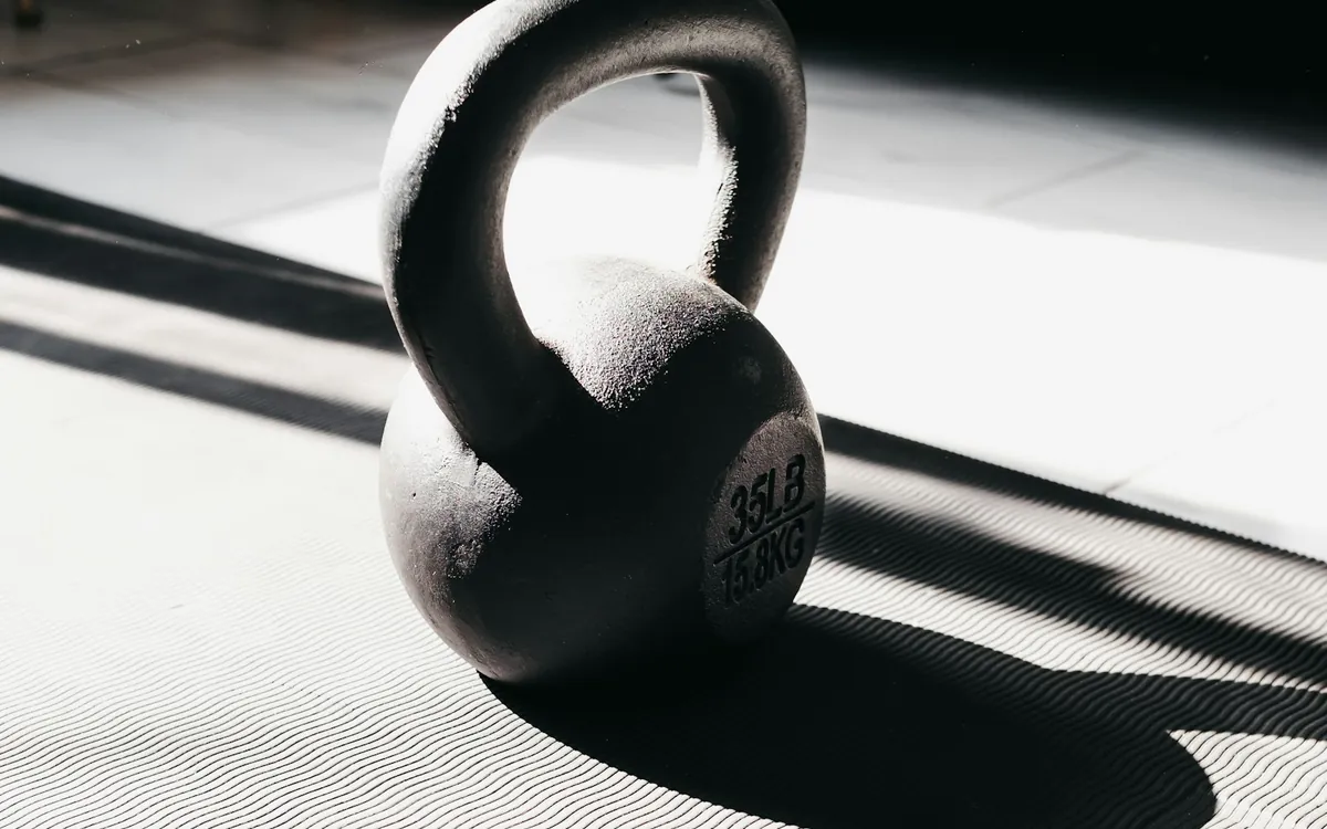 A kettlebell casting a shadow across an exercise mat; illustrative stock photo