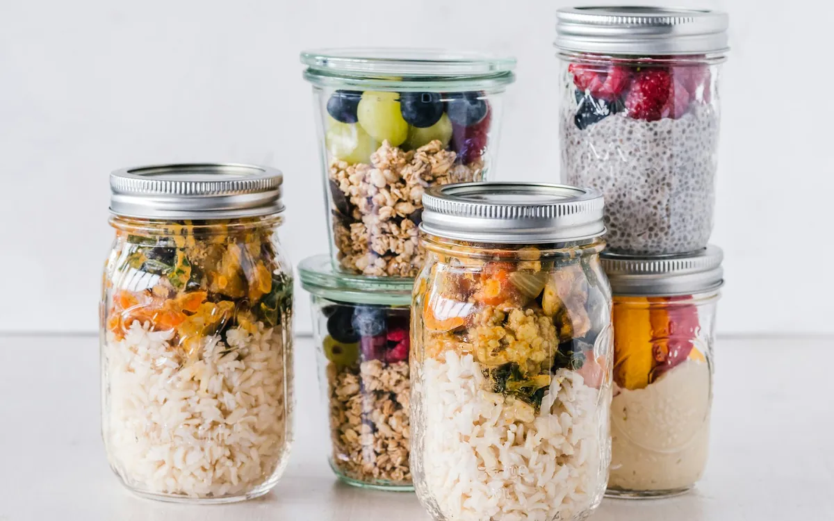 Glass jars holding prepared grains, vegetables, fruit, and oats; illustrative stock photo