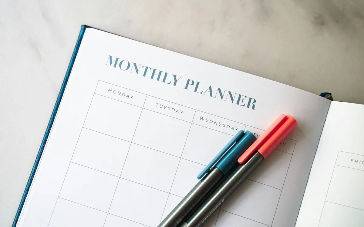 An open monthly planner with two pens; illustrative stock photo