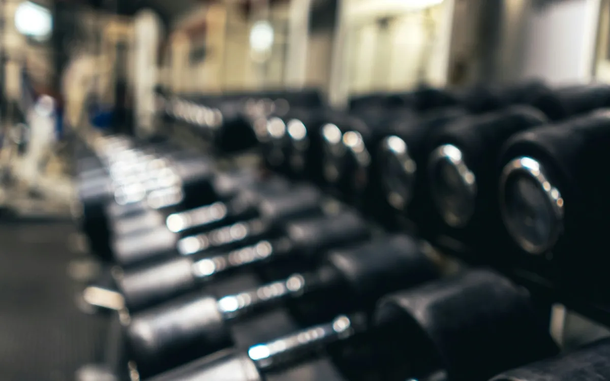 Rows of round black dumbbells on a rack; illustrative stock photo